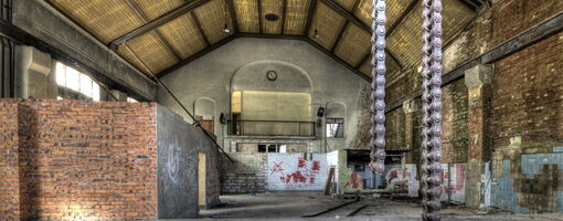 Geräumige Industriehalle mit Ketten und Graffiti.
